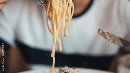A person uses forks to twirl and eat delicious creamy mushroom spaghetti.