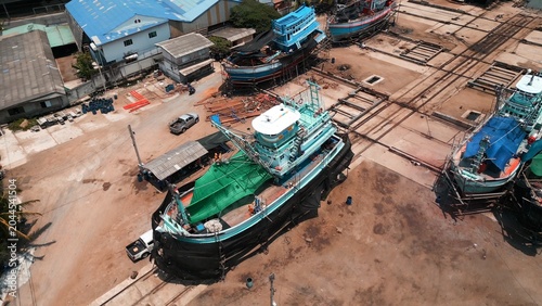 Fotografie Fishing boats undergoing construction and repair in a busy industrial shipyard