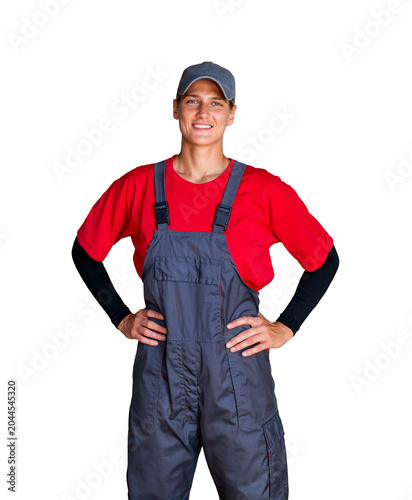 Confident female technician worker in bib overalls standing with hands on hips.