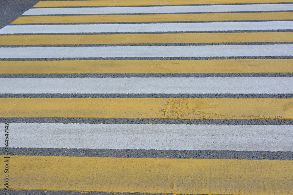 Fototapeta premium Yellow and White Striped Crosswalk on Asphalt Road close up