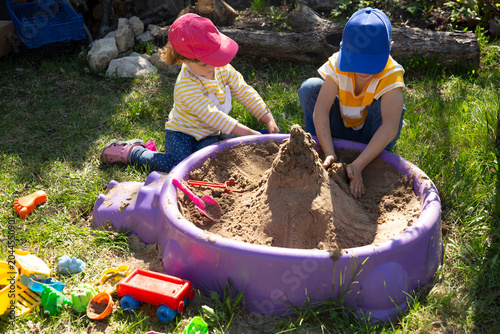 Canvastavla two children brother and sister play with sand in a sandbox in the garden on a summer day