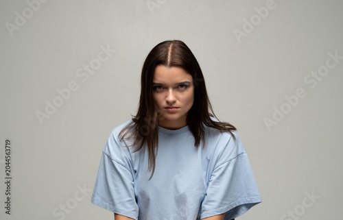 Tableau sur toile Young woman looking intense and serious in a studio setting, conveying anger, fr