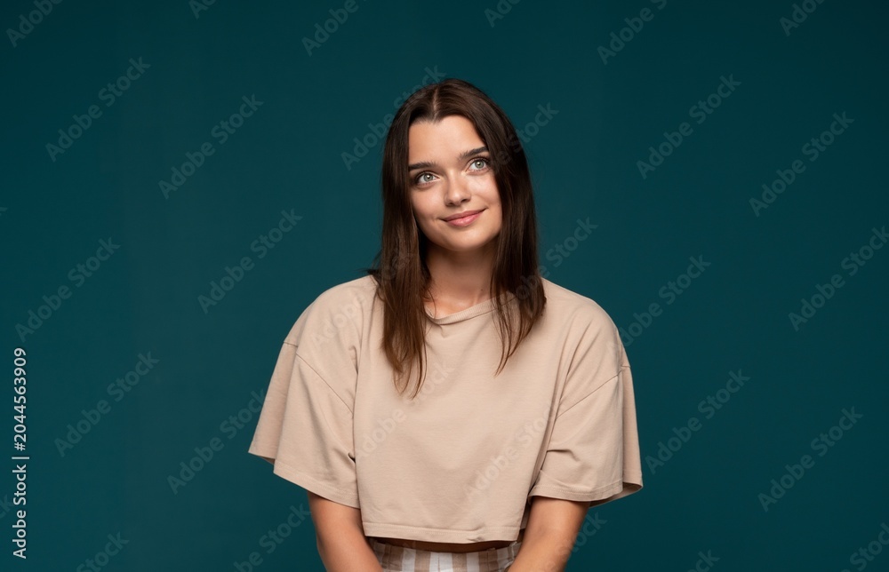 Obraz premium Young woman looking up with thoughtful expression, daydreaming with ideas and inspiration on blue background