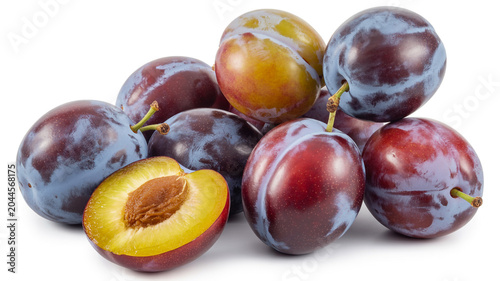 Fresh ripe purple plums with one cut in half revealing a pit and golden flesh
