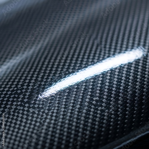 Abstract texture of black carbon fiber material with light reflection, high tech