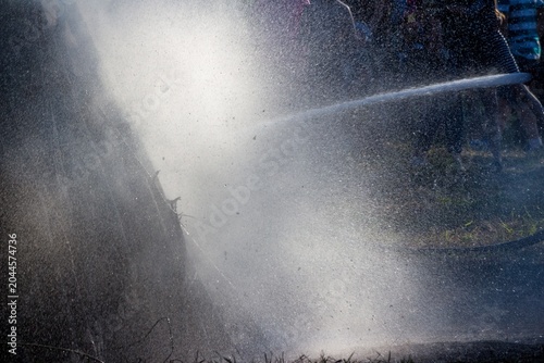 Quadro su tela Powerful water jet extinguishing a large bonfire at a summer folk festival, crea