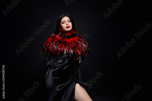 Brunette Woman in Black Dress with Red Feather Collar in a Glamorous and Stylish Portrait