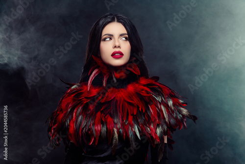 Mysterious elegant woman in red feather costume posing confidently against a smoky background