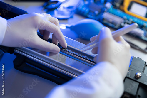 A technician focuses on repairing an electronic device in a lab setting using various tools and equipment at night