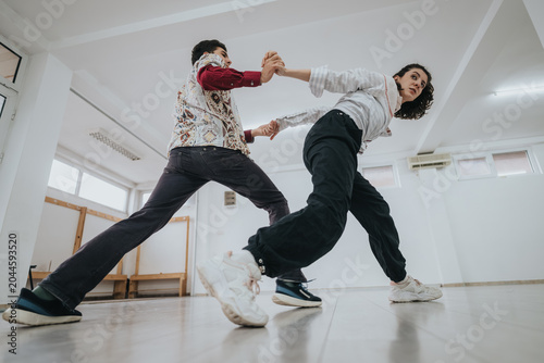 Fotografie Two dancers practice a partnered contemporary routine in a bright studio