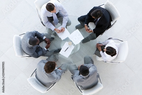 Overhead view of diverse professionals in a meeting, collaborating around a glass table