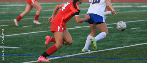 Players Chase Ball During a Soccer Match on a Field in the Evening