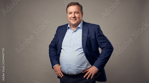 Confident Middle Aged Overweight Businessman in Suit Standing Against Grey Background