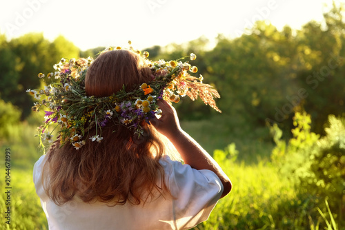 Girl in flower wreath rear view close up on sunny meadow, natural background. Floral crown, symbol of summer solstice. ceremony for Midsummer, Litha, Ligo holidays. Pagan slavic fest Ivan Kupala