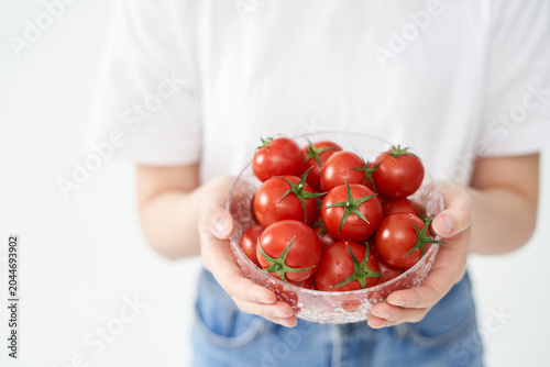The young woman is holding tomato.

