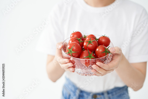 The young woman is holding tomato.
