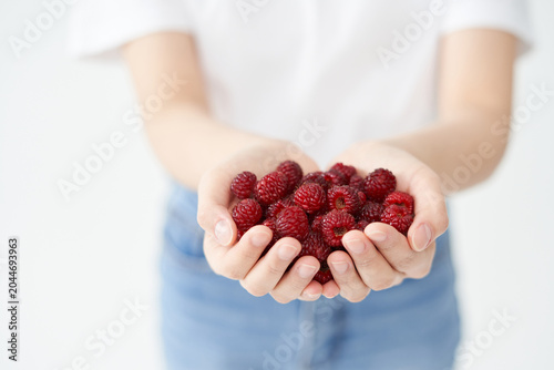 The young woman is holding raspberry.

