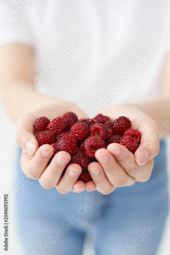 The young woman is holding raspberry.
