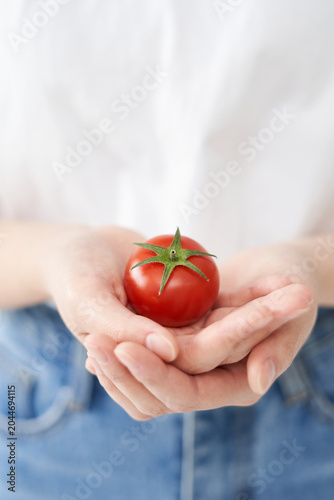 The young woman is holding tomato.
