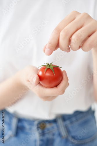 The young woman is holding tomato.
