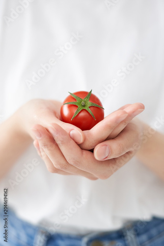 The young woman is holding tomato.
