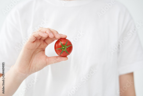 The young woman is holding tomato.
