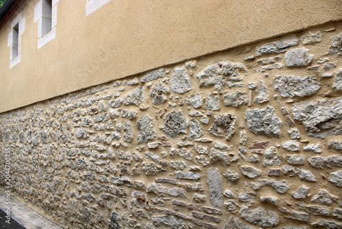 Mur en pierre jointoyée en soubassement, surmonté d’une partie haute en crépi ocre
