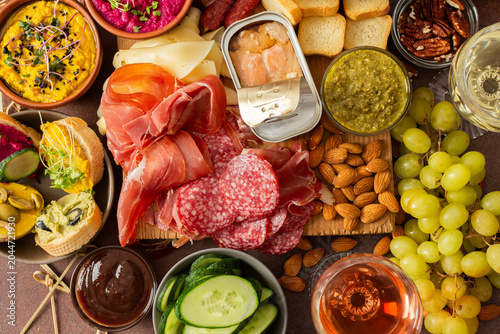 Schilderij op canvas Enjoy a vibrant charcuterie board filled with assorted cheeses, savory sausages, creamy hummus, nuts, and colorful vegetables