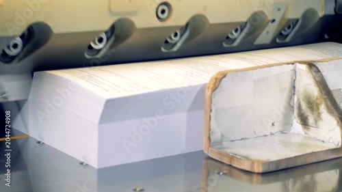 Industrial guillotine cutting stack of printed paper sheets