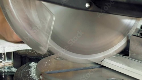 Worker Cutting White Plastic Trim with Miter Saw in Workshop