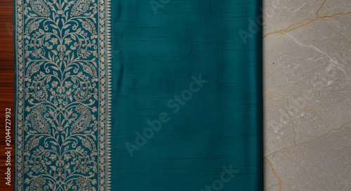 Close up of green indian silk fabric with intricate golden border.