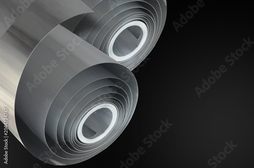 Valokuva two thin silver aluminum sheets rolled into a cylindrical shape against a solid