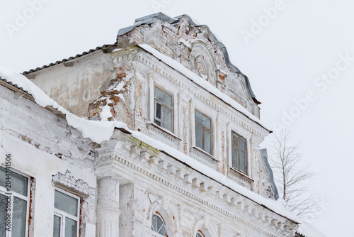 Obraz na plátně Abandoned historic building showing ornate classical facade, peeling plaster and broken windows under fresh winter snow