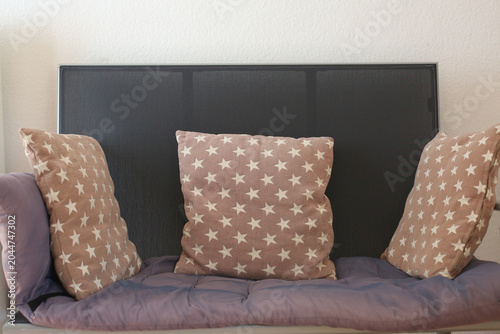 Three decorative cushions placed on comfortable indoor bench. Cozy home interior with soft textiles and minimalist decor in warm neutral colors