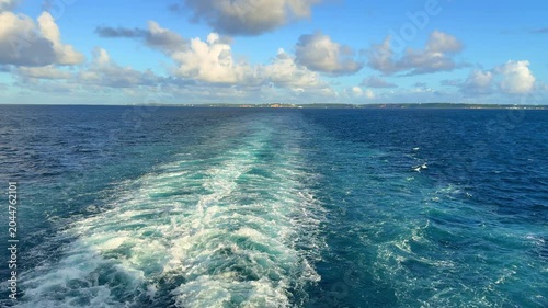 A Cruise ship wake on a beautiful sunny day with white clouds and blue seas on the Atlantic Ocean.