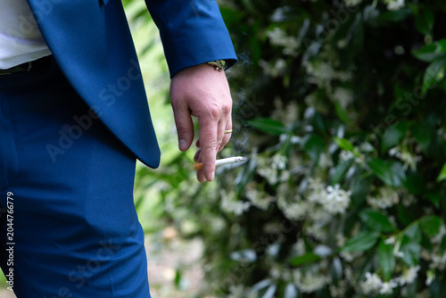 Man in blue suit holding burning cigarette
