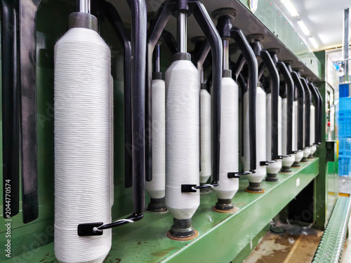 Automatic yarn winding machine with white bobbins and black metal arms