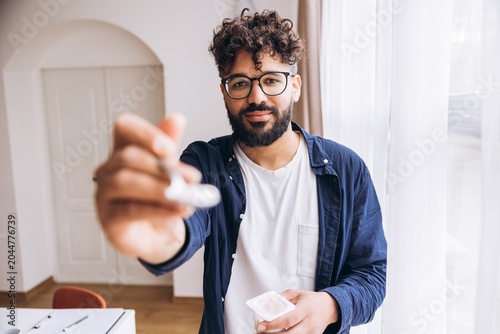 Konstfotografi Smiling happy middle eastern man extending spoon with yogurt for a healthy snack