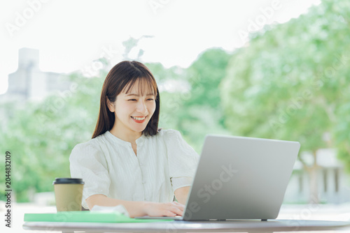 Fotografija テラスでパソコンを使う若い女性