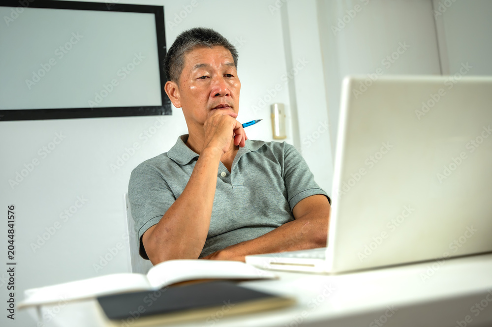 Naklejka premium Serious senior construction manager studying building plans at working desk, concentrating deeply on troubleshooting design errors during a tight deadline