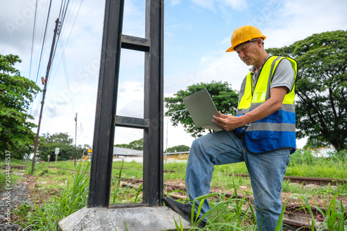 Tableau sur toile Senior Japanese train engineer working outdoor at rail tracks inspecting railway