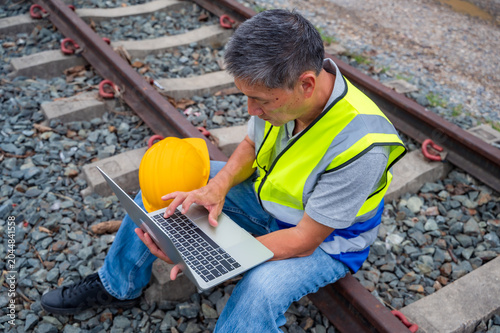 Schilderij op canvas Senior Japanese train engineer working outdoor at rail tracks inspecting railway
