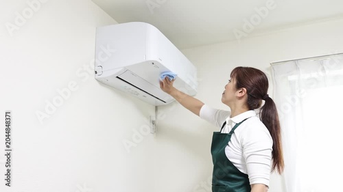 家庭用エアコンを清掃する女性スタッフ