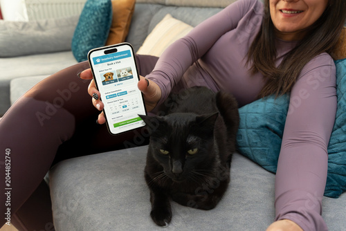 Woman using smartphone veterinary app booking cat appointment