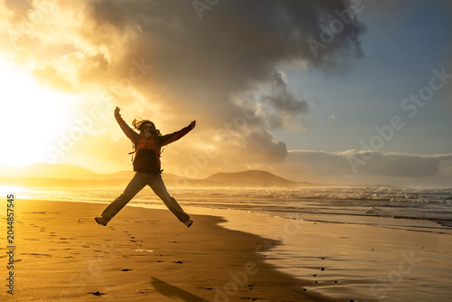 Fotografie Person walks along the serene Famara Beach in Lanzarote, leaving footprints in the sand