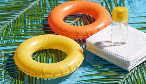 Colorful inflatable pool rings on tropical background