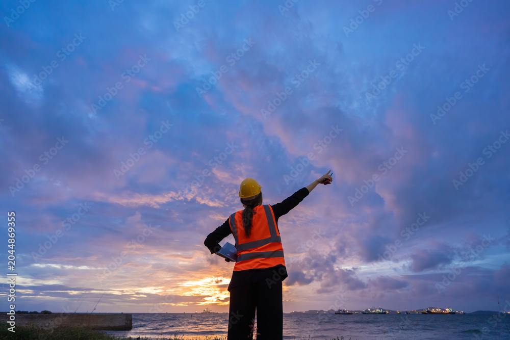 Fototapeta premium Asian female engineer evaluating Energy assets at dusk, contributing to Industry advancement, Oil refinery optimization, environmental management, and industrial innovation.