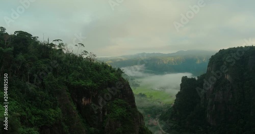 Aerial drone view of foggy cliff with vast mountain landscape and depth