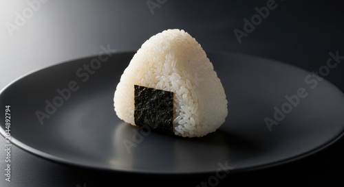 Delicious onigiri Japanese rice ball with seaweed on black plate