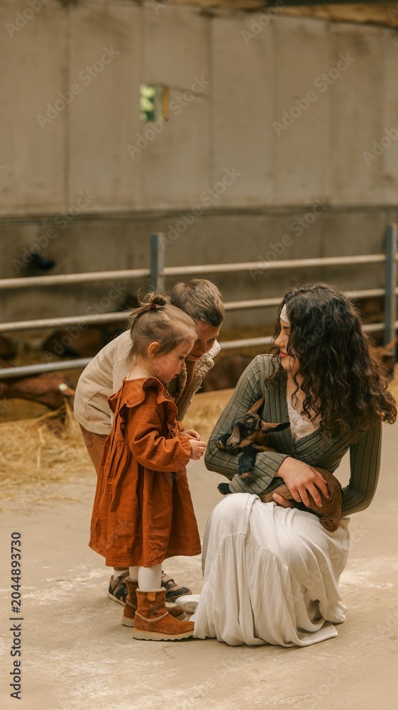 Obraz premium Family bonding with a newborn goat on a rustic farm